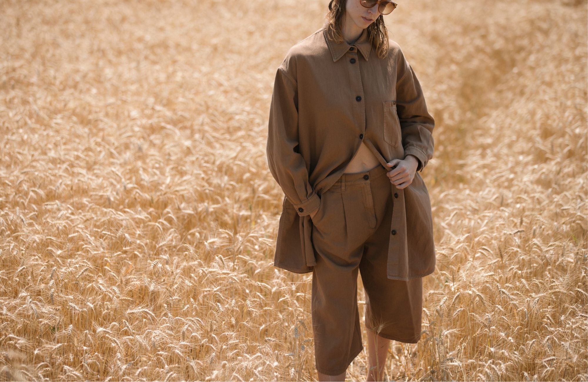 Donna con completo camicia e bermuda color tabacco in un campo di grano, SS26 Barmas