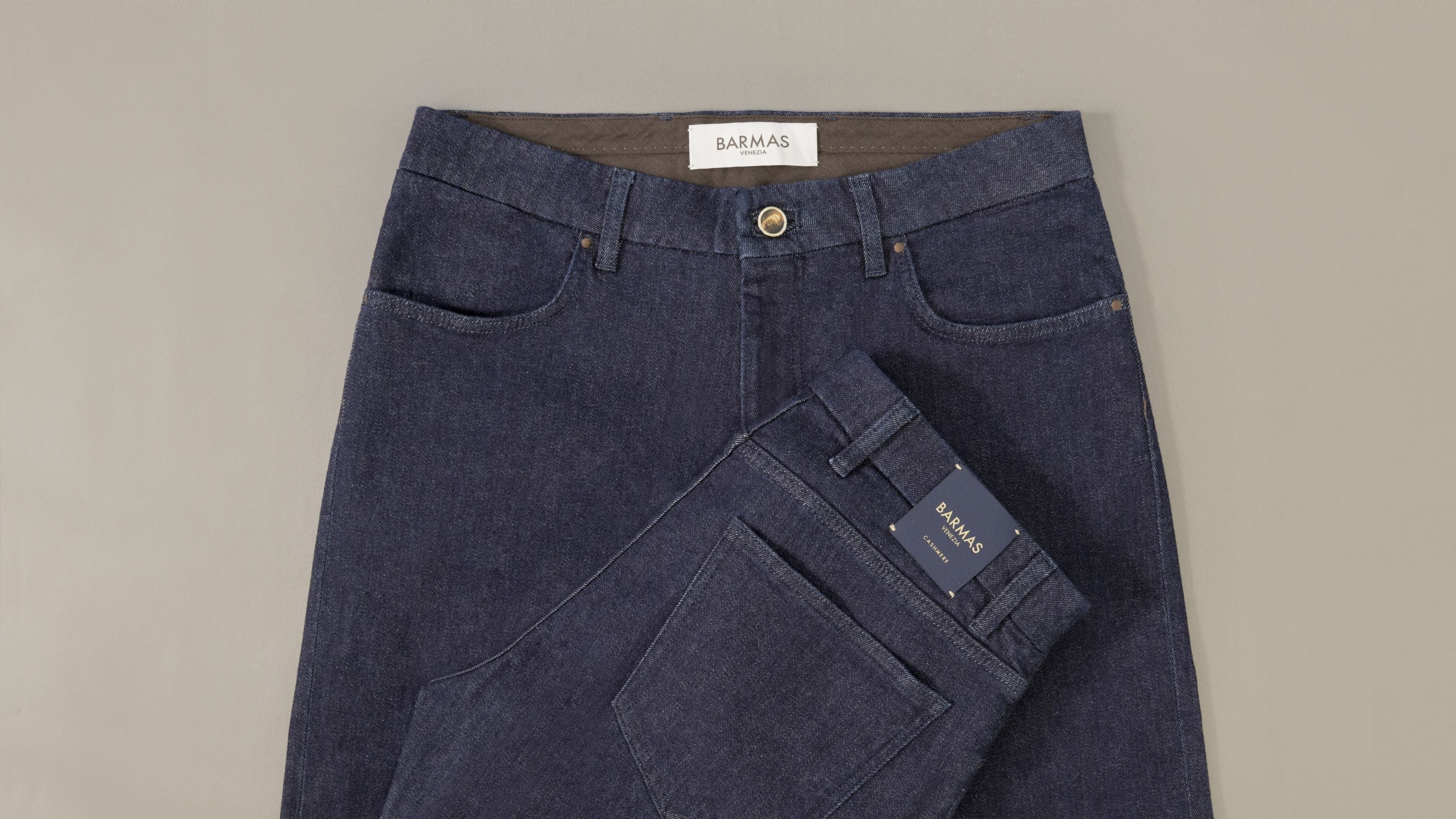 Jeans Barmas piegati su fondo grigio
