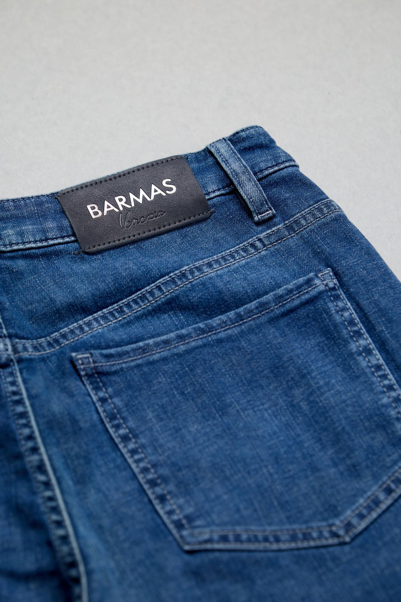 Dettaglio di jeans blu Barmas con patch posteriore e cuciture sartoriali.