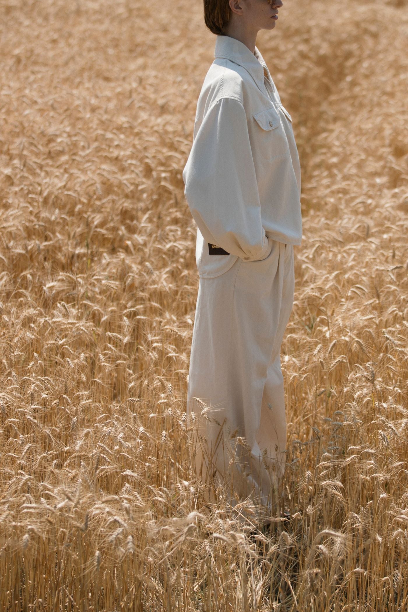 Total look ecru Barmas indossato in campo di grano.