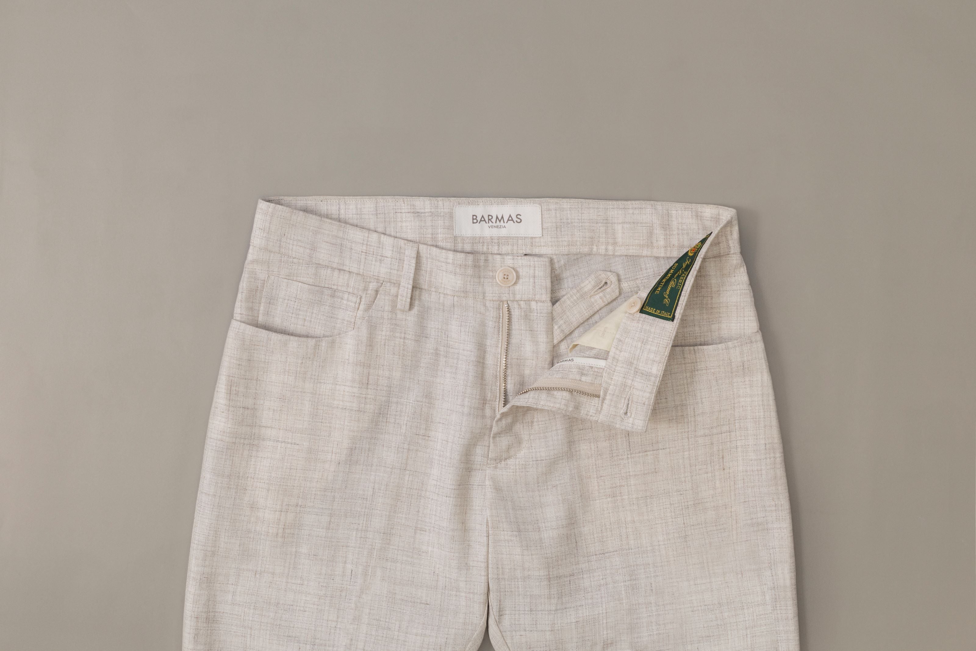 Pantalone Barmas bianco con zip aperta su fondo grigio.